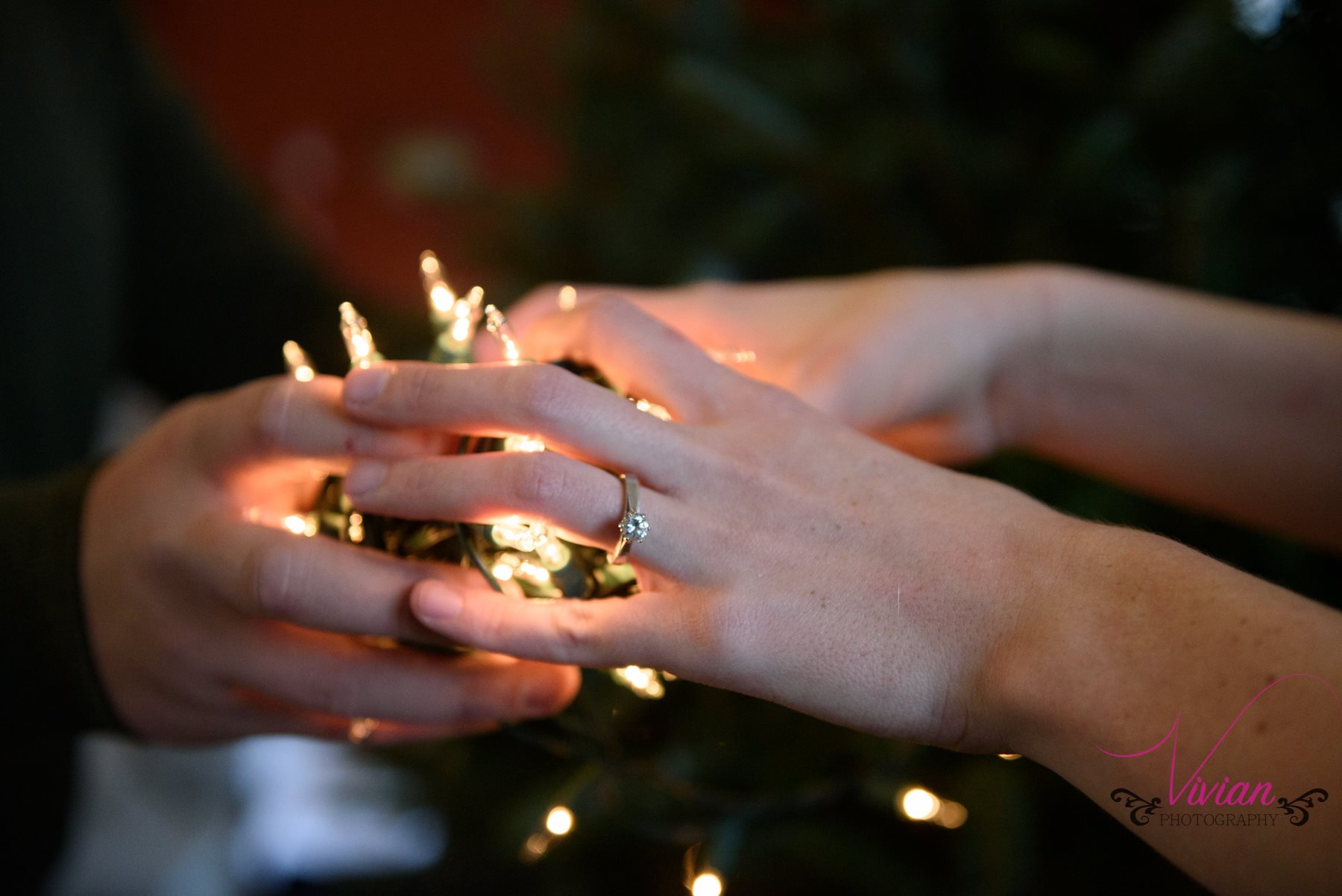 couple-clasping-christmas-lights-engagement-ring.jpg