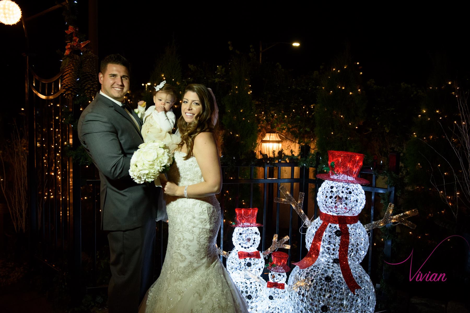 bride-groom-holding-baby-posing-near-christmas-decorations.jpg