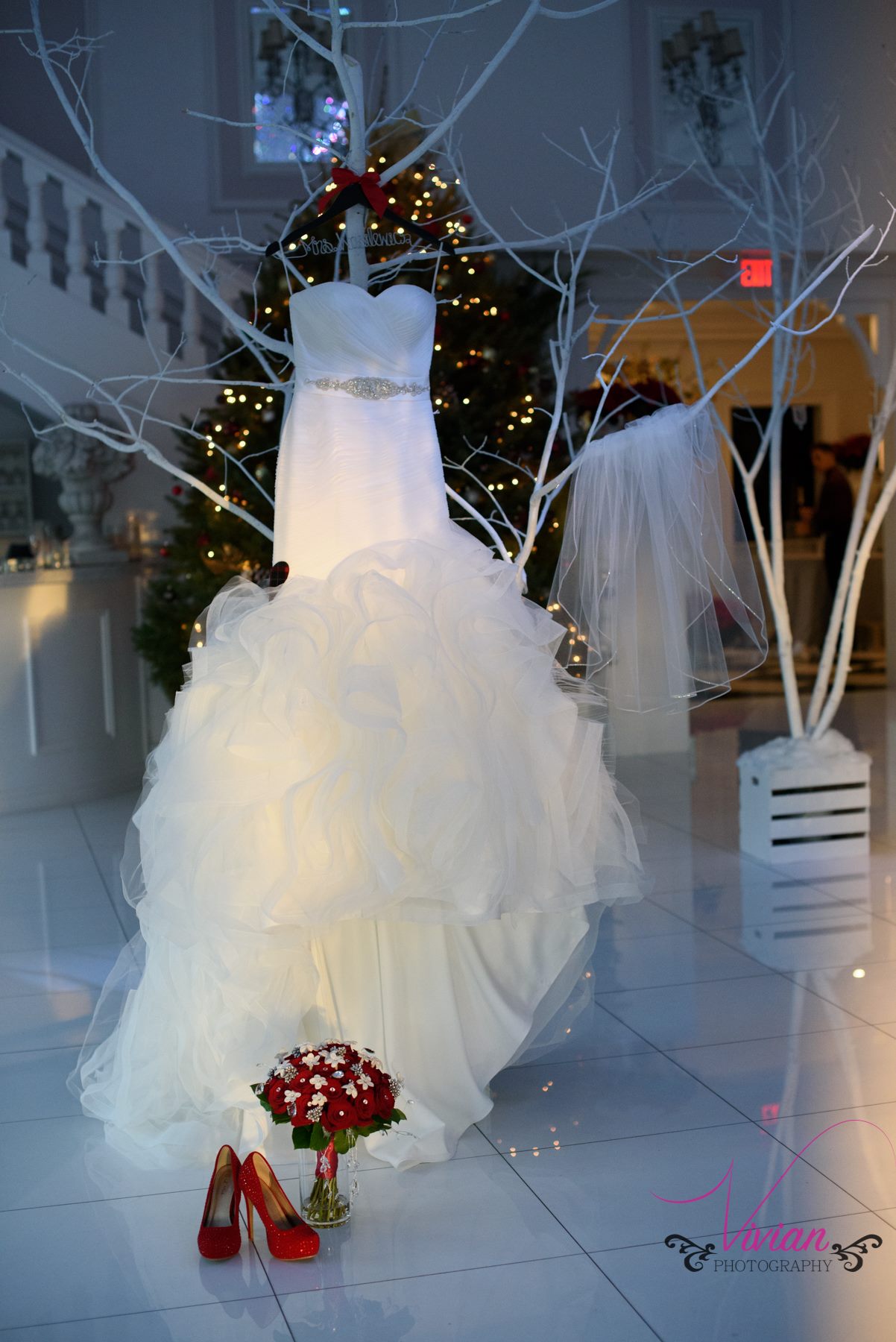 wedding-dress-hanging-from-white-tree-branches-near-red-heels.jpg