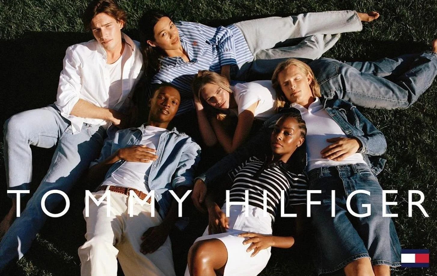 Advertising image from Tommy Hilfiger showing a group of men and women outside on a lawn all laying down
