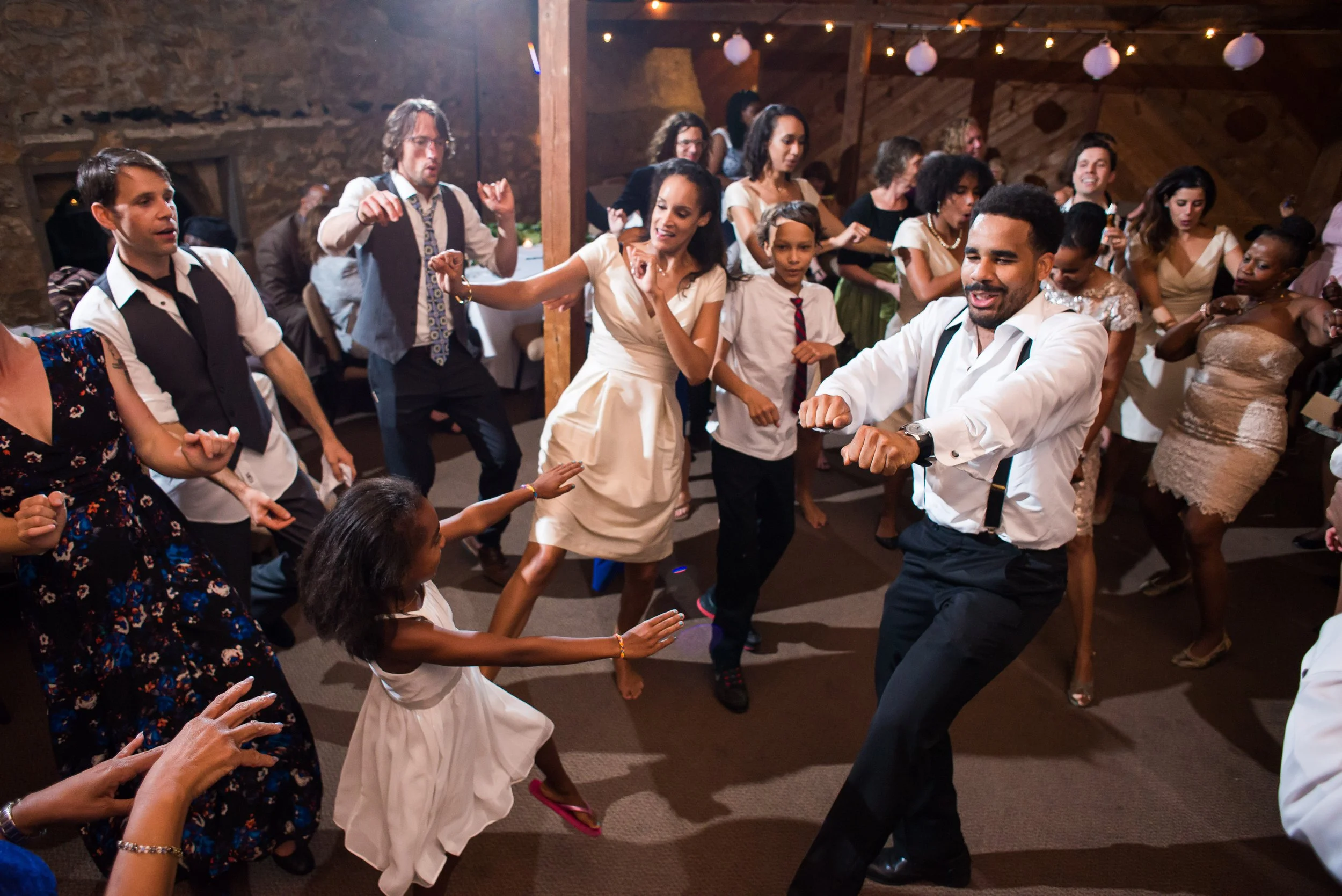 People dancing at a wedding ceremony with a floral backdrop and a portrait in the background.