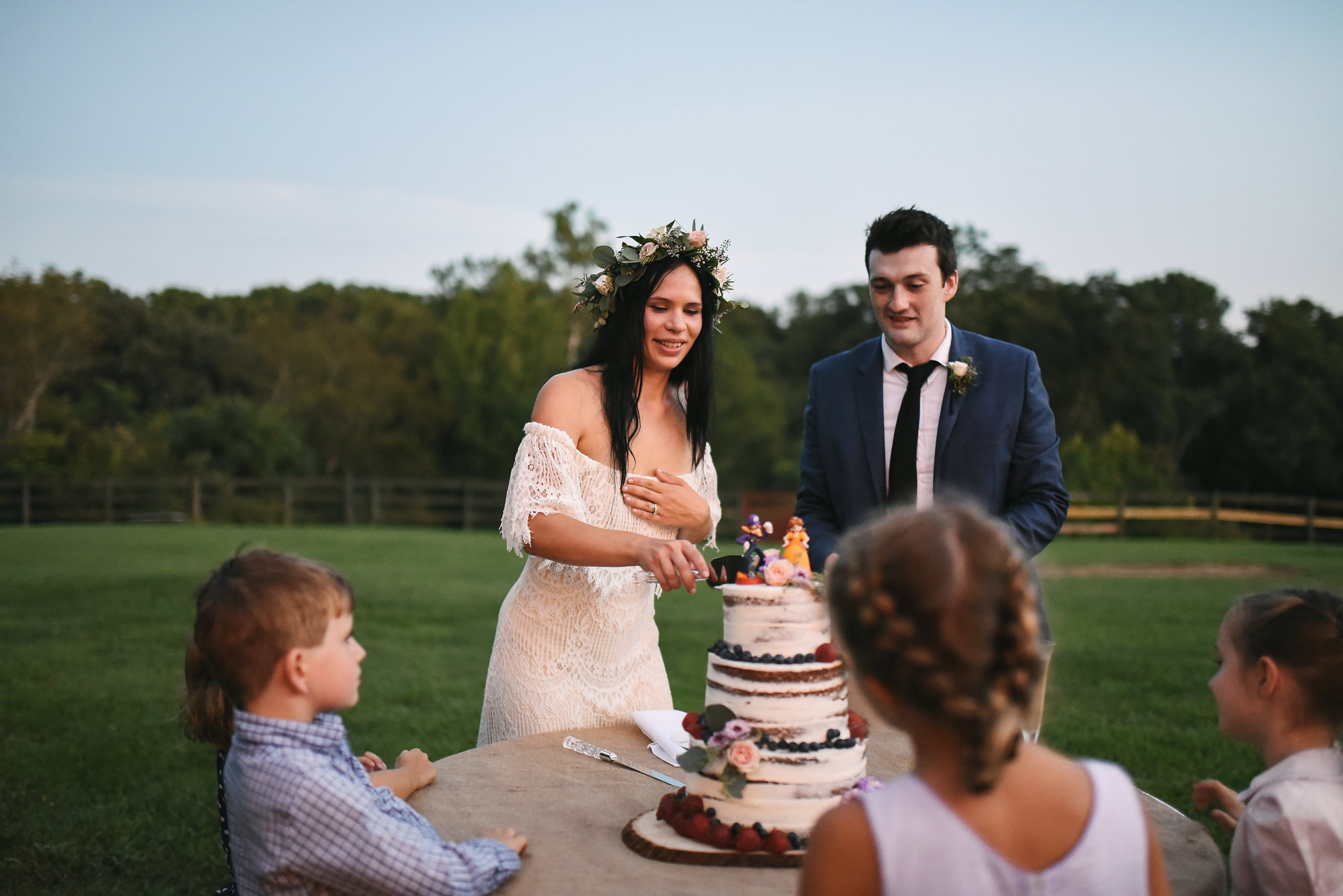  Maryland, Eastern Shore, Baltimore Wedding Photographer, Romantic, Boho, Backyard Wedding, Nature, Bride and Groom Cutting the Cake While Kids Watch, Honey Hive Bakery, Flower Crown, Outdoor Reception 