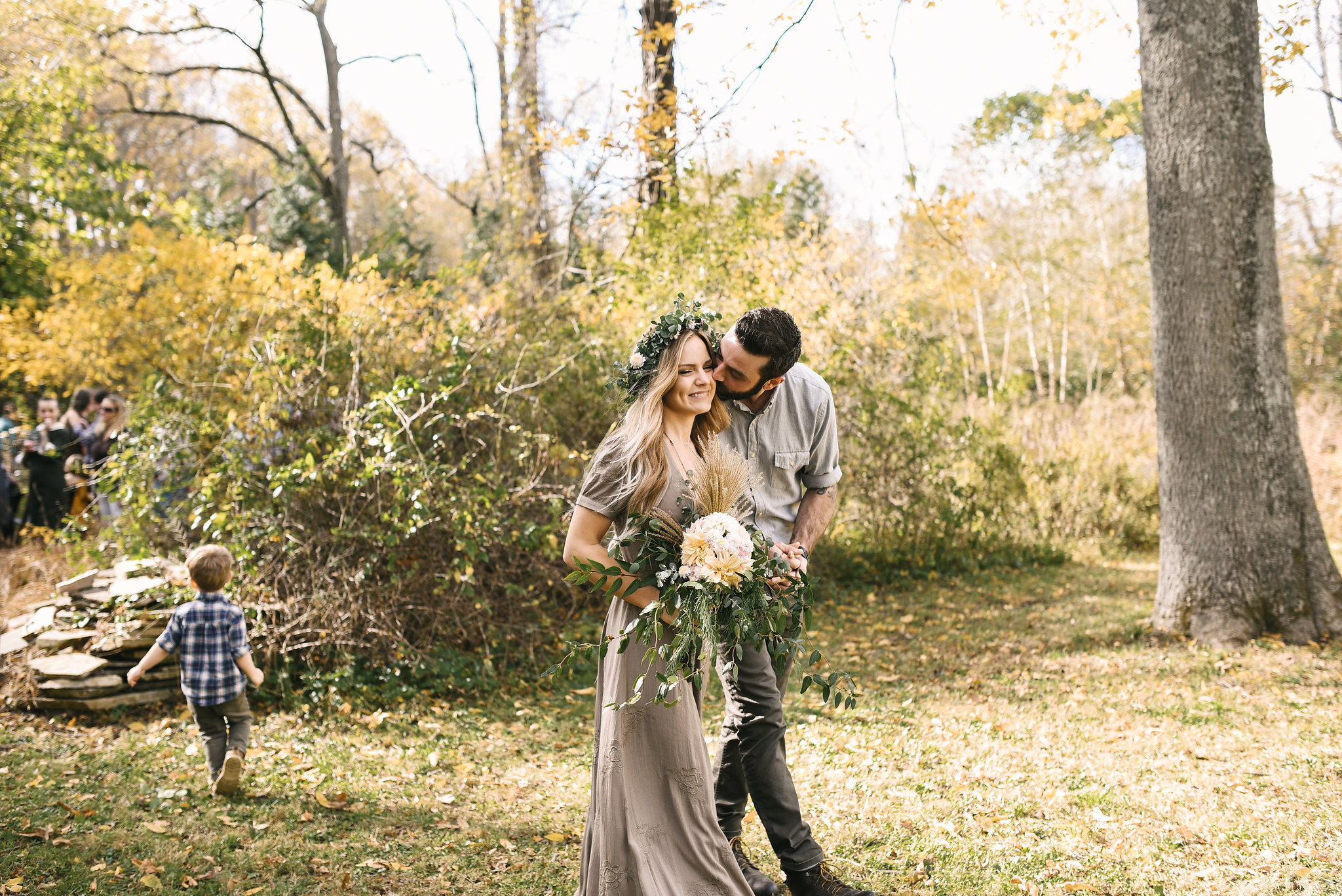 Baltimore, Maryland Wedding Photographer, Backyard Wedding, DIY, Rustic, Casual, Fall Wedding, Woodland, Groom Kissing Bride on the Cheek While Their Son Runs Around, Butterbee Farm