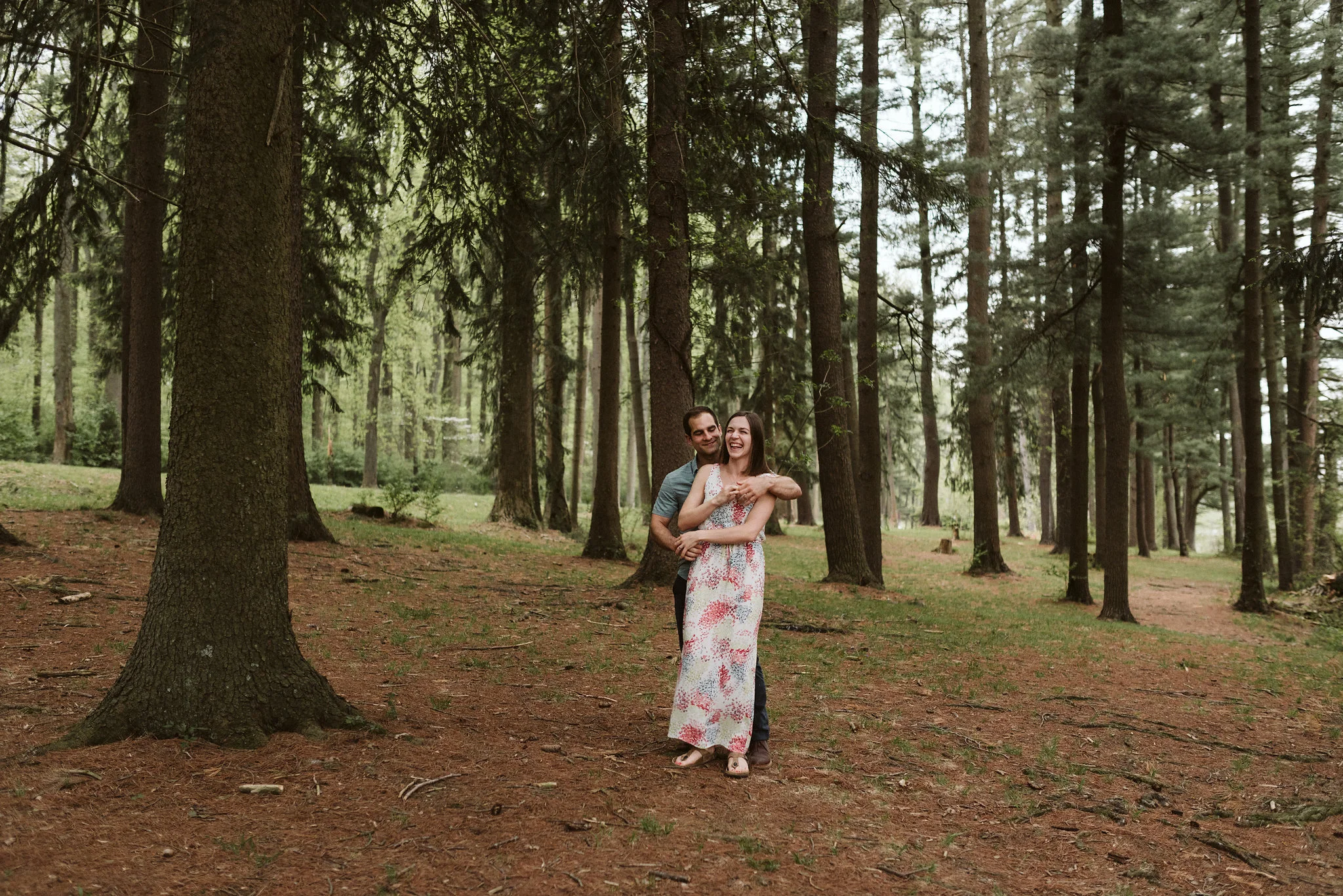 romantic couple dancing in forest on bed of pine needles