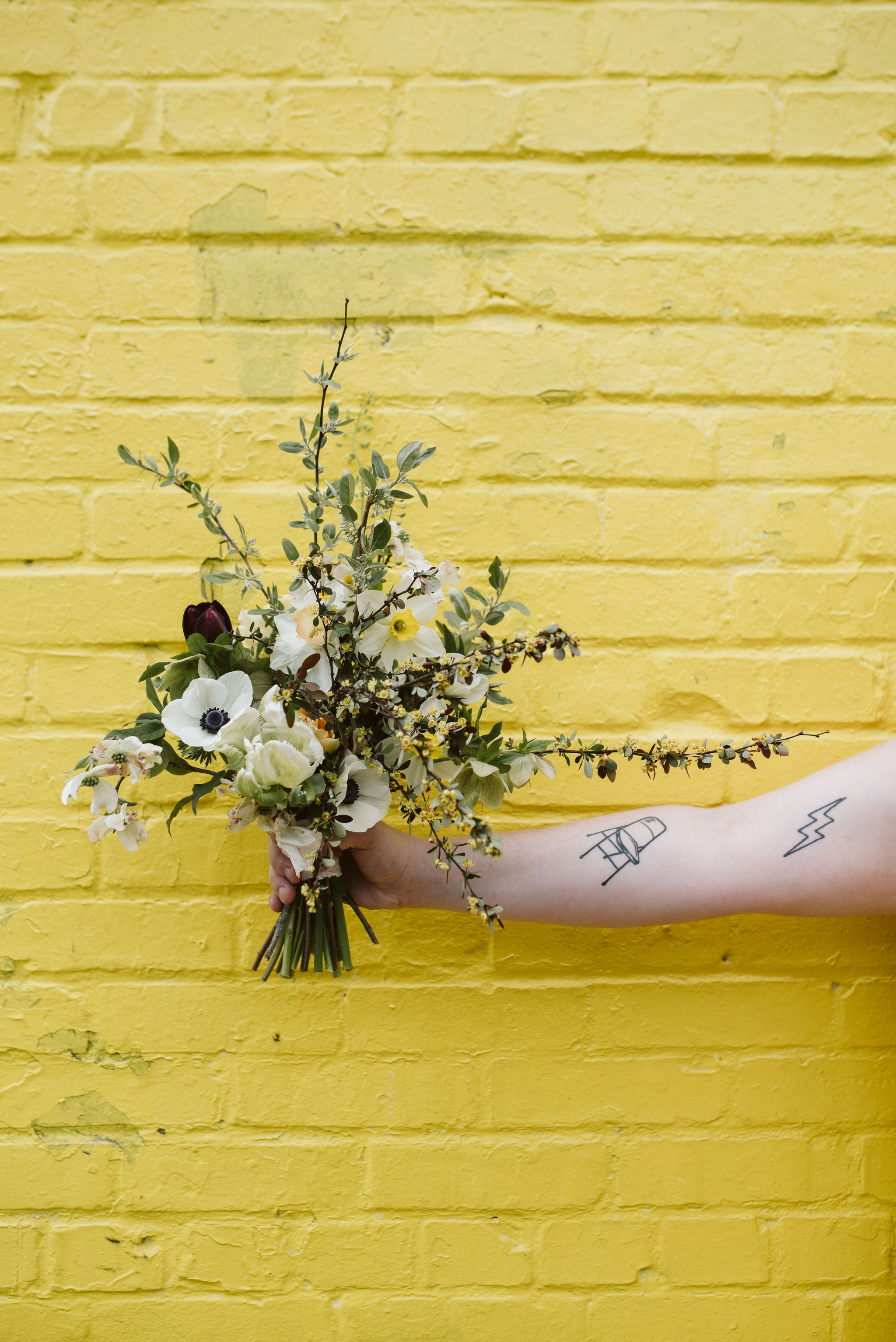  Washington DC, Baltimore Wedding Photographer, Alexandria, Old Town, Jewel Tone, Romantic, Modern, Tattoos, Bride holding out bouquet in front of brick wall, White anemones and tulips 