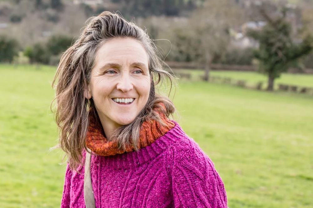 Uma Dinsmore-Tuli smiling in a green field.