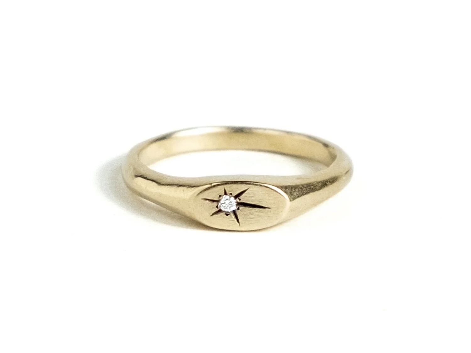 Slim gold signet ring with a star-set diamond on the top face