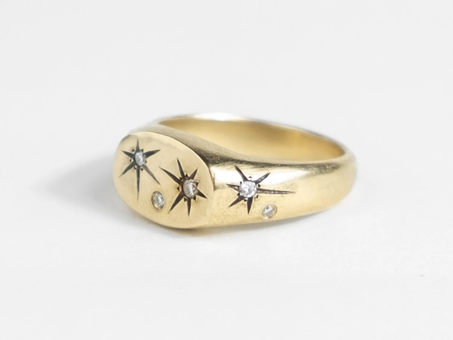 Side view of a wide gold signet ring with star-set diamonds all over the top