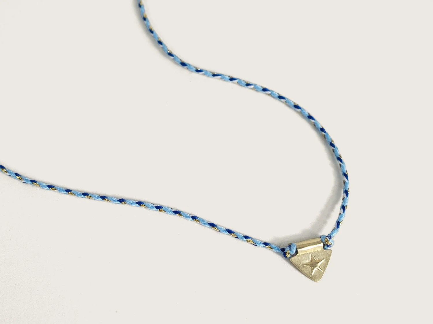 Gold star and triangle charm on a braided blue cord