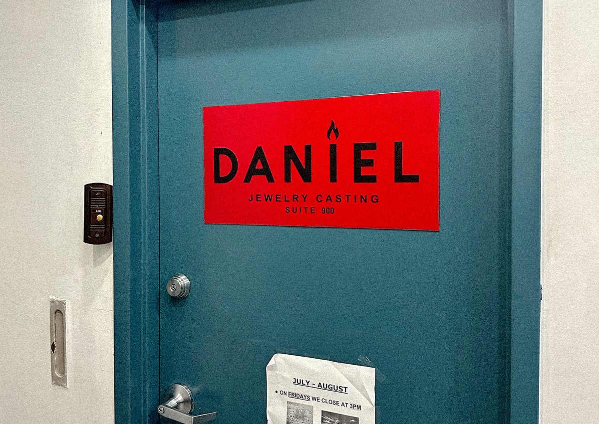 A closed door in a hallway with a sign on it that says "Daniel Jewelry Casting"