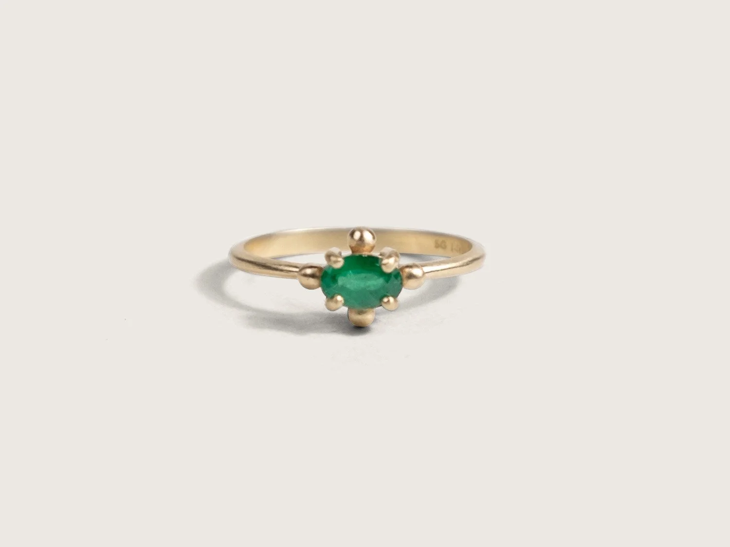 Thin gold ring with an oval emerald in the center