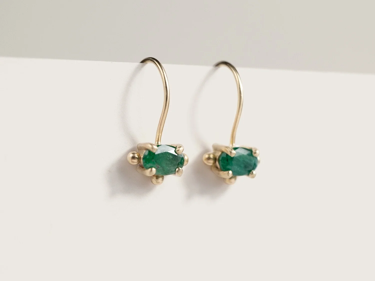 Gold drop earrings with oval emeralds