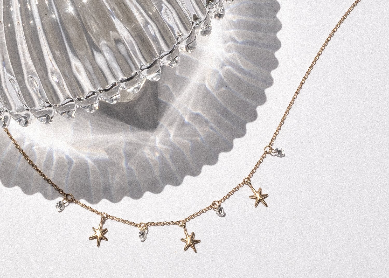 Glass reflections over a gold and diamond star necklace
