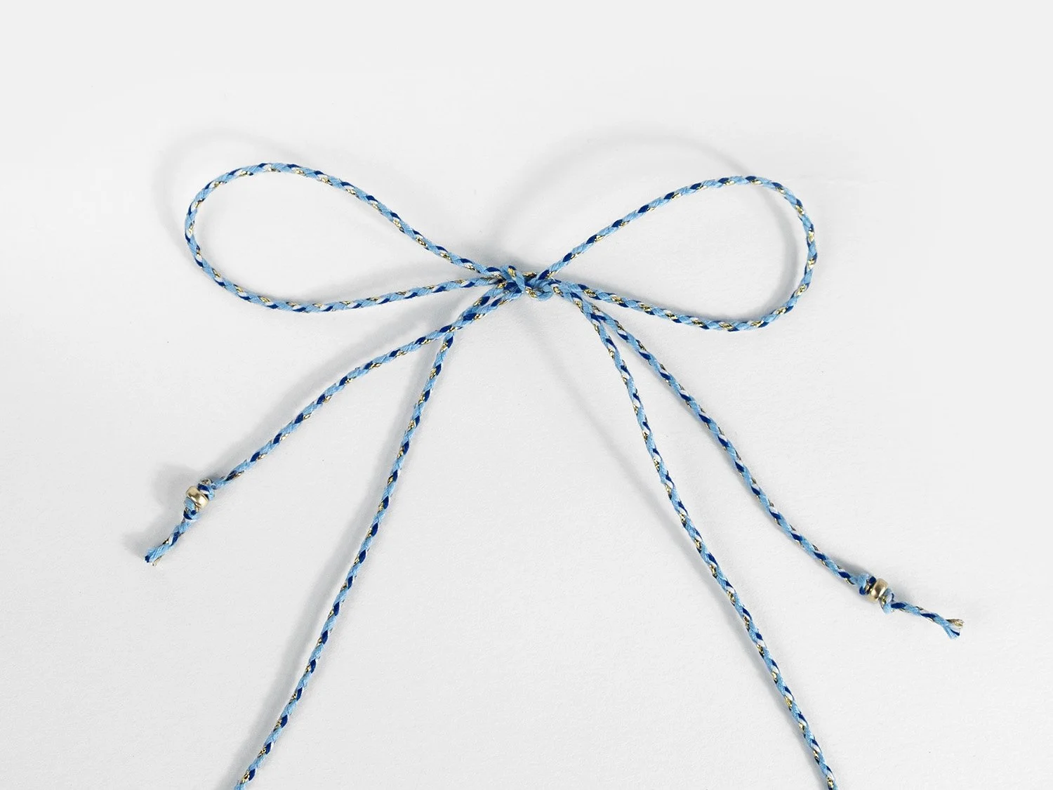 Braided cord tied in a knot with gold beads tied to the ends