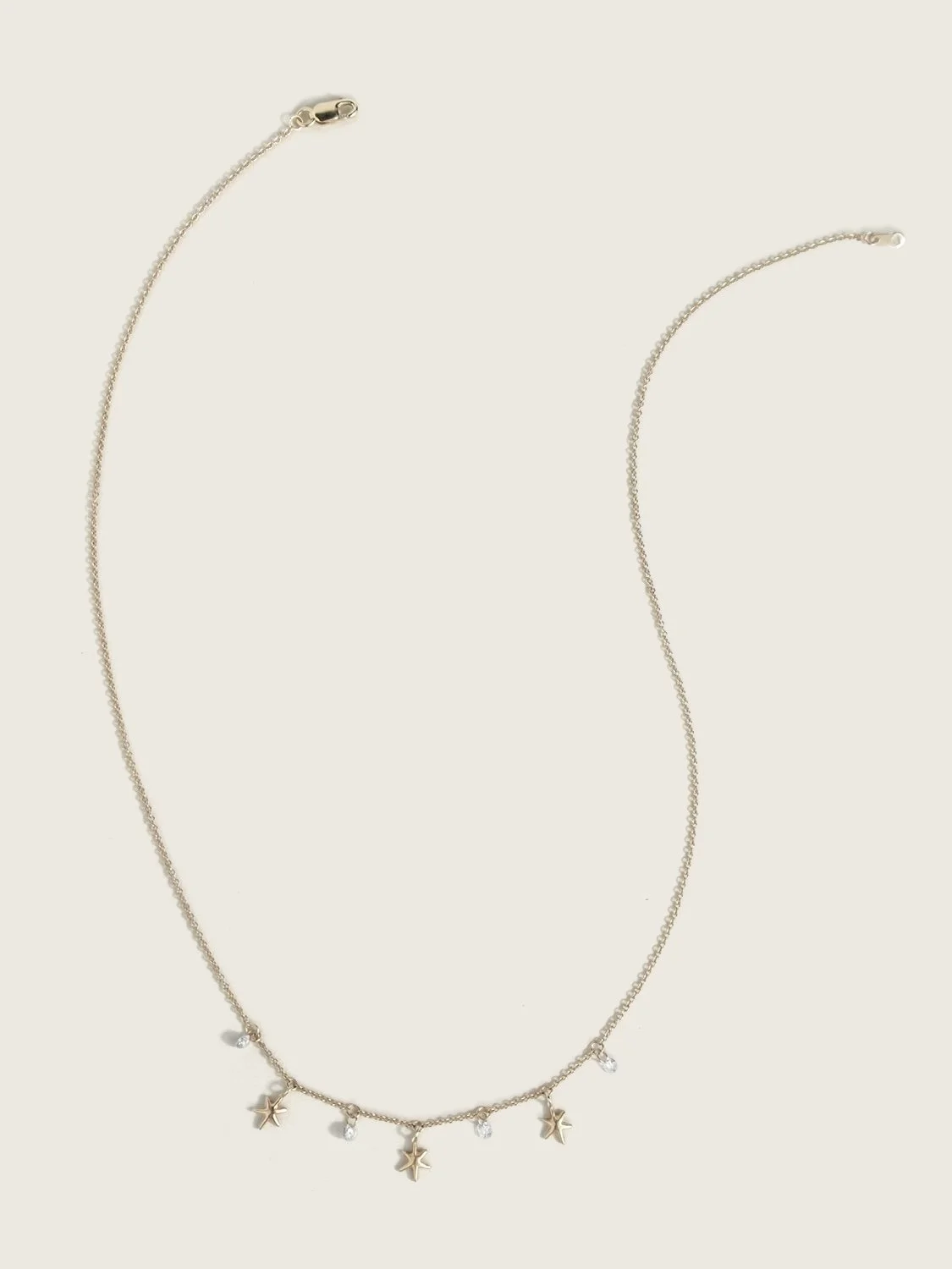 Gold necklace with hanging gold stars and white diamonds