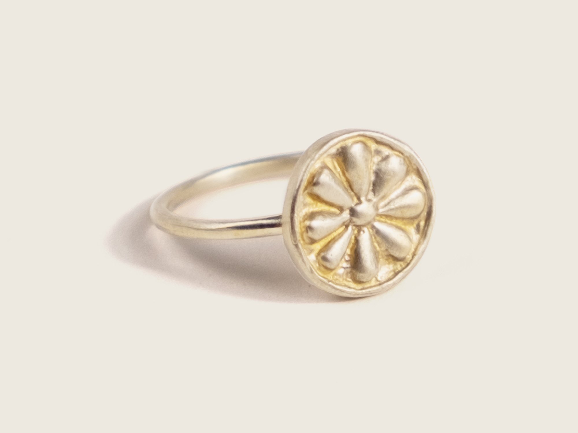 Side view of a thin gold ring with an oversized, round floral motif on top (Copy)