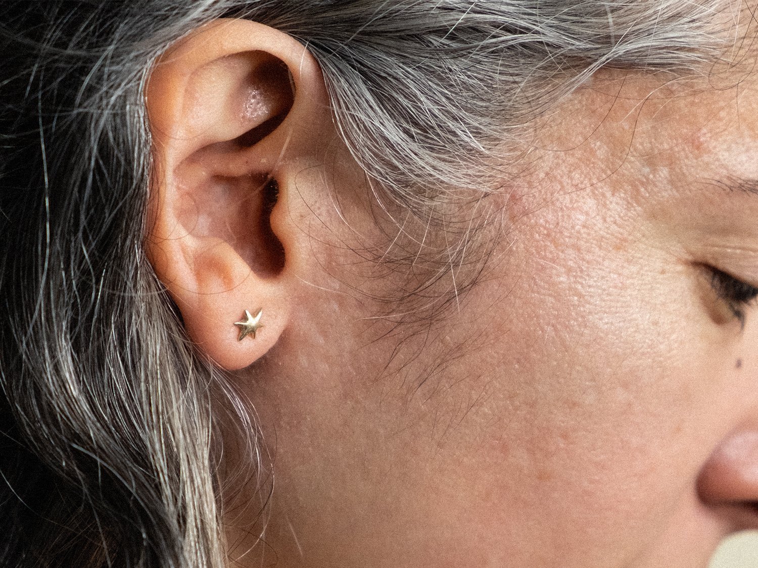 Close up of female model wearing gold star stud earrings