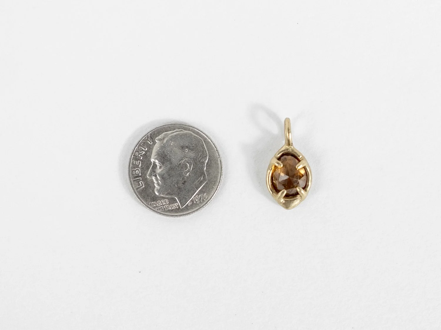 14k gold and golden zircon charm next to a dime