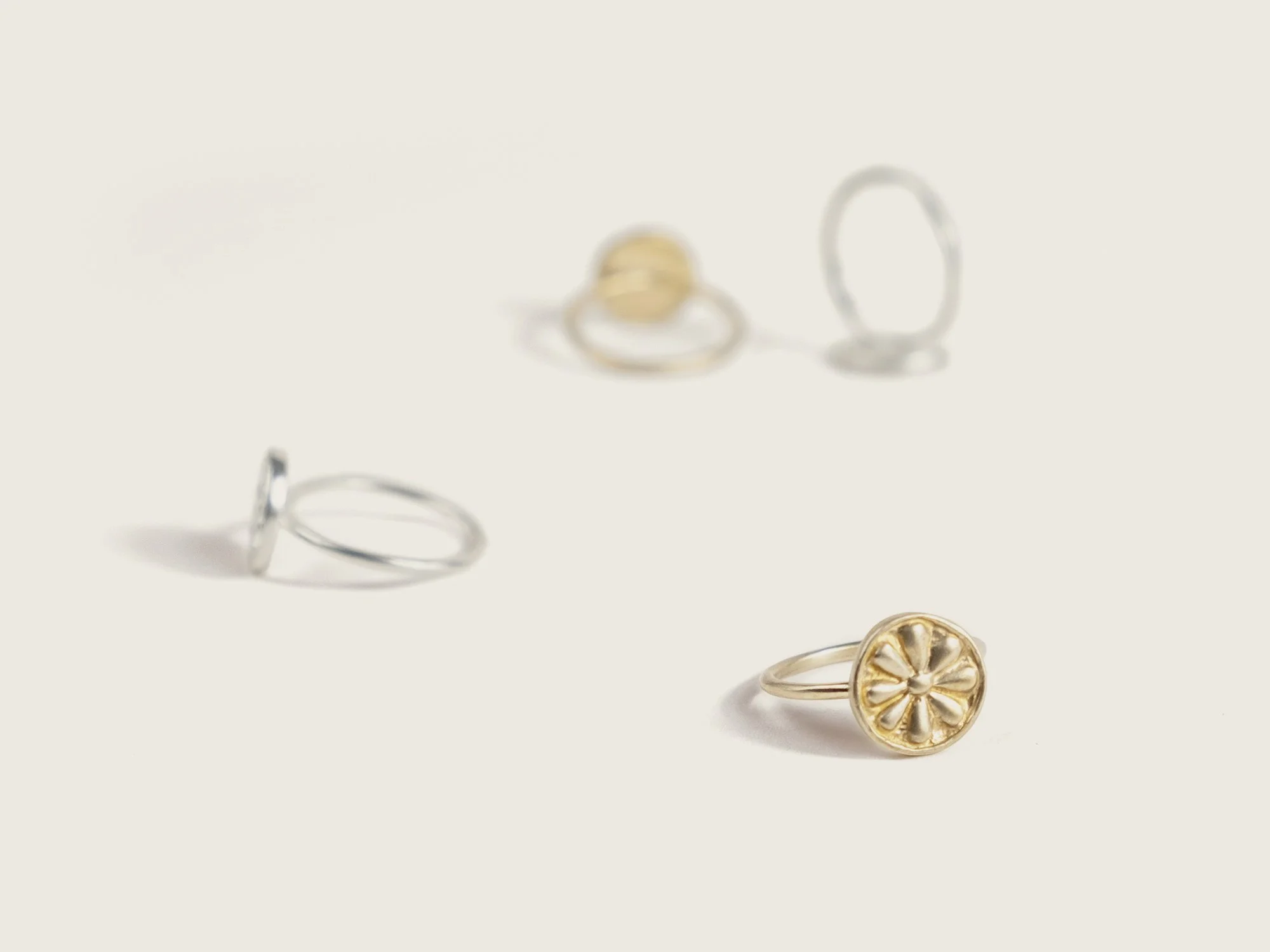 Many of the same ring in gold and silver scattered along a surface (Copy)