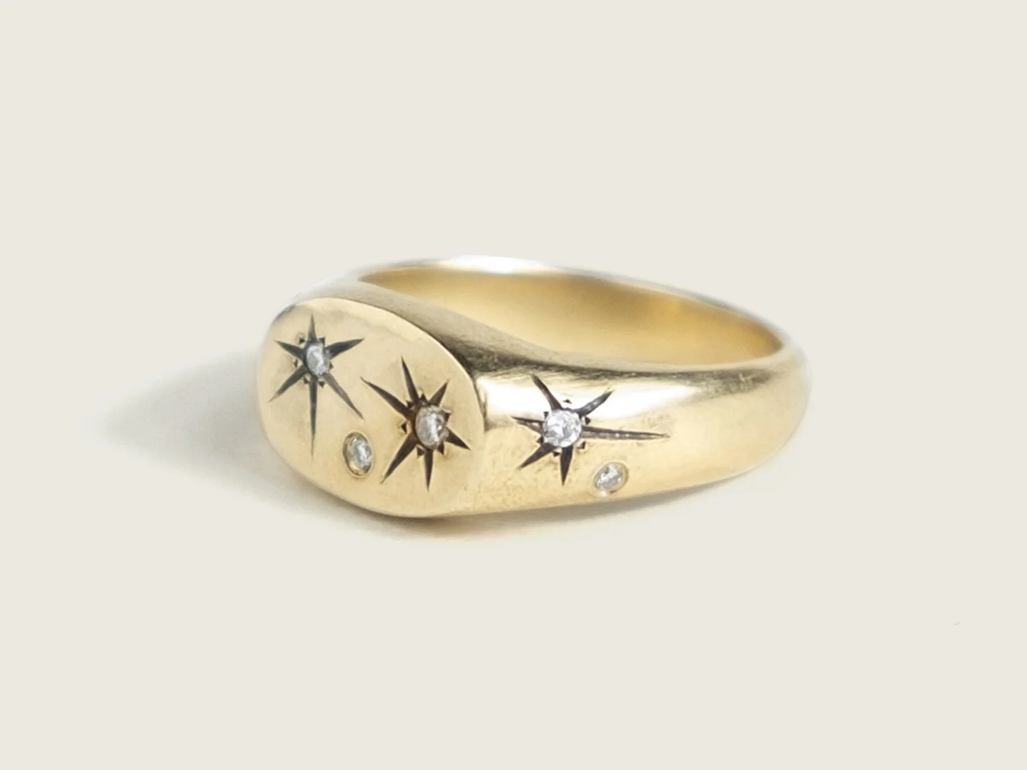 Side view of a wide gold signet ring with star-set diamonds all over the top