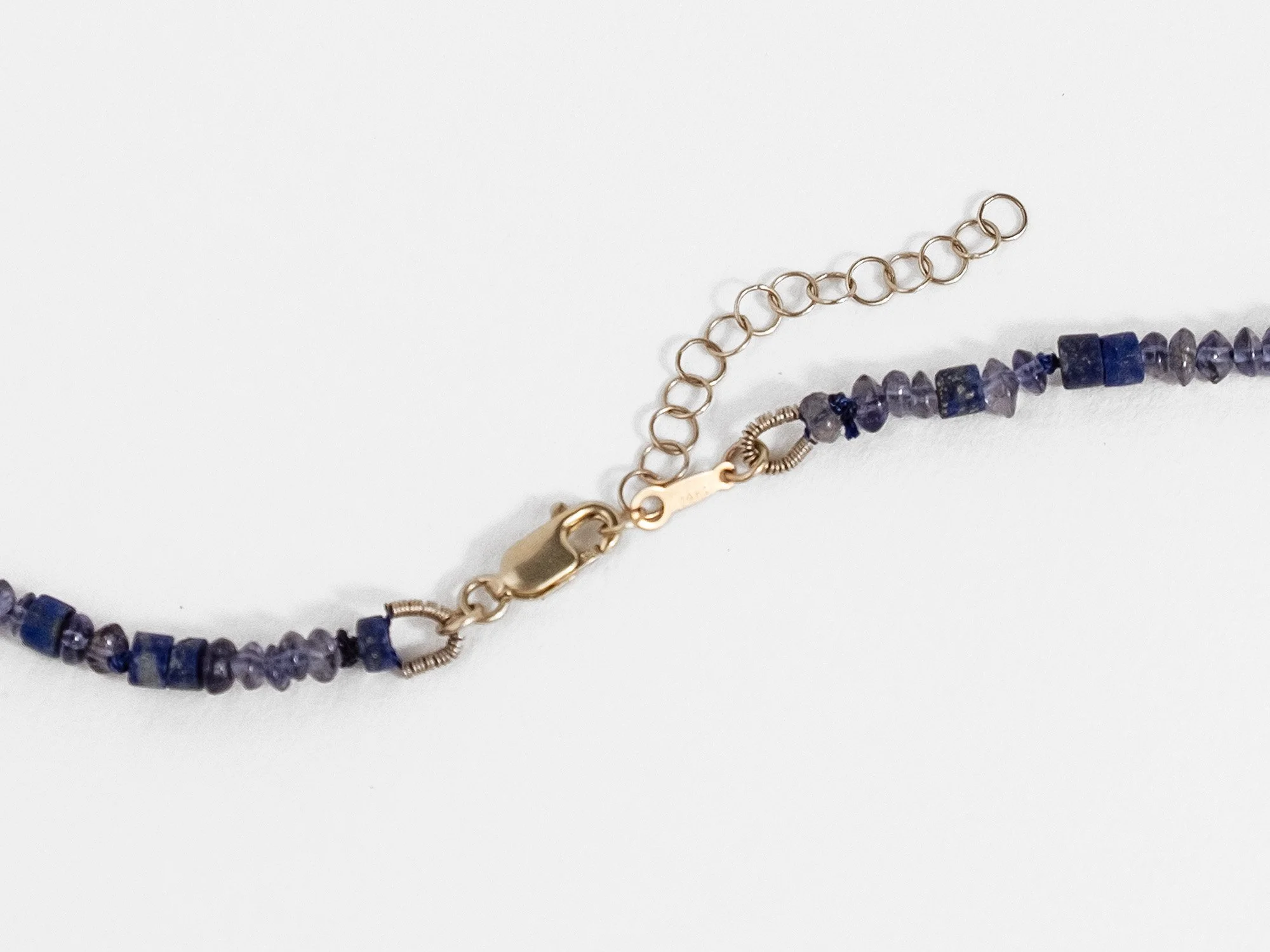 Necklace with beads in dark-blue indigo stones and a center gold heart pendant