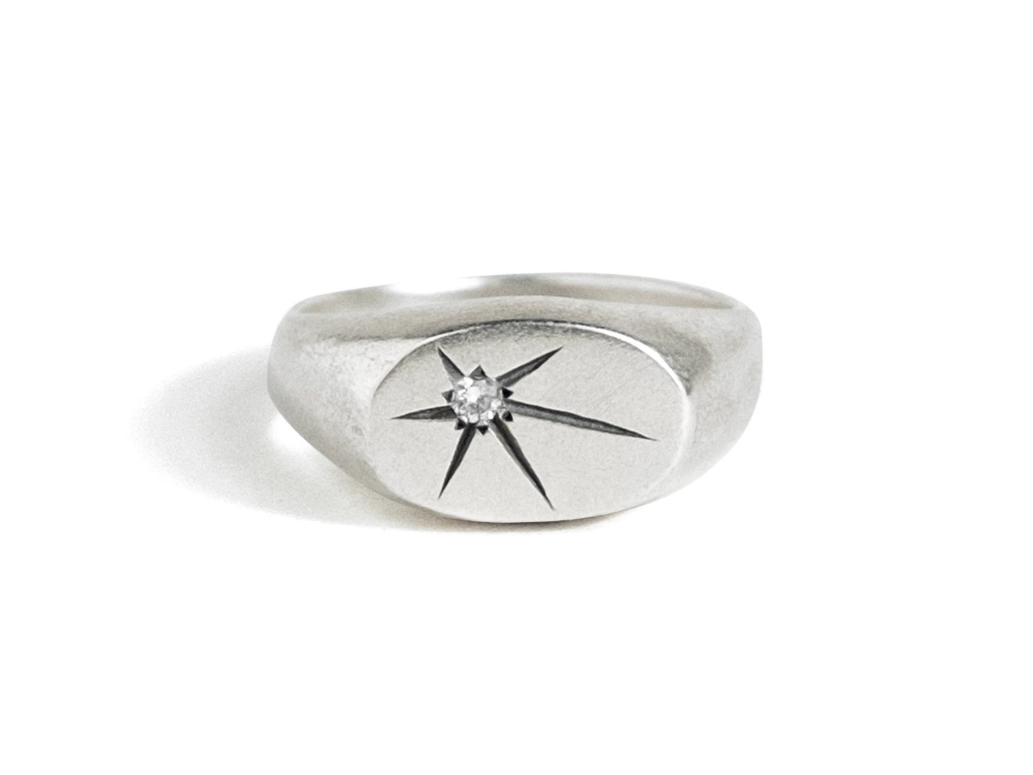 Wide silver signet ring with a single star-set diamond on the flat face