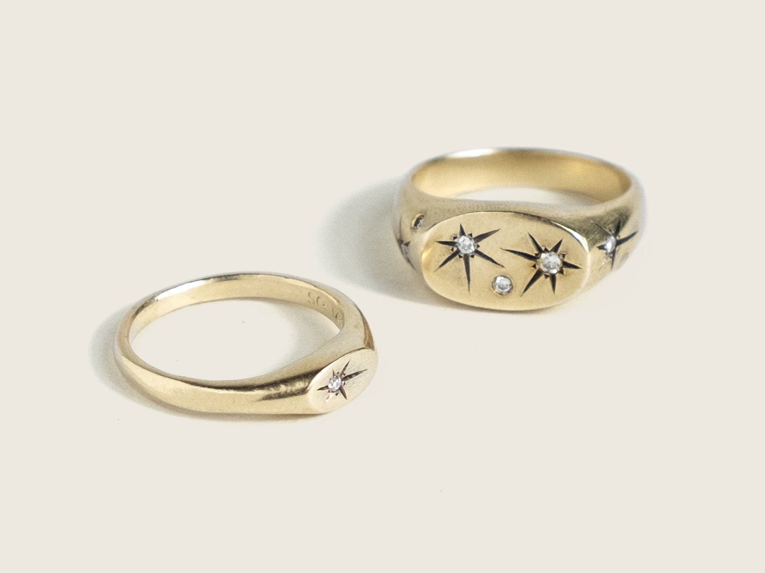 Pair of thin and wide gold signet rings with star-set diamonds on each