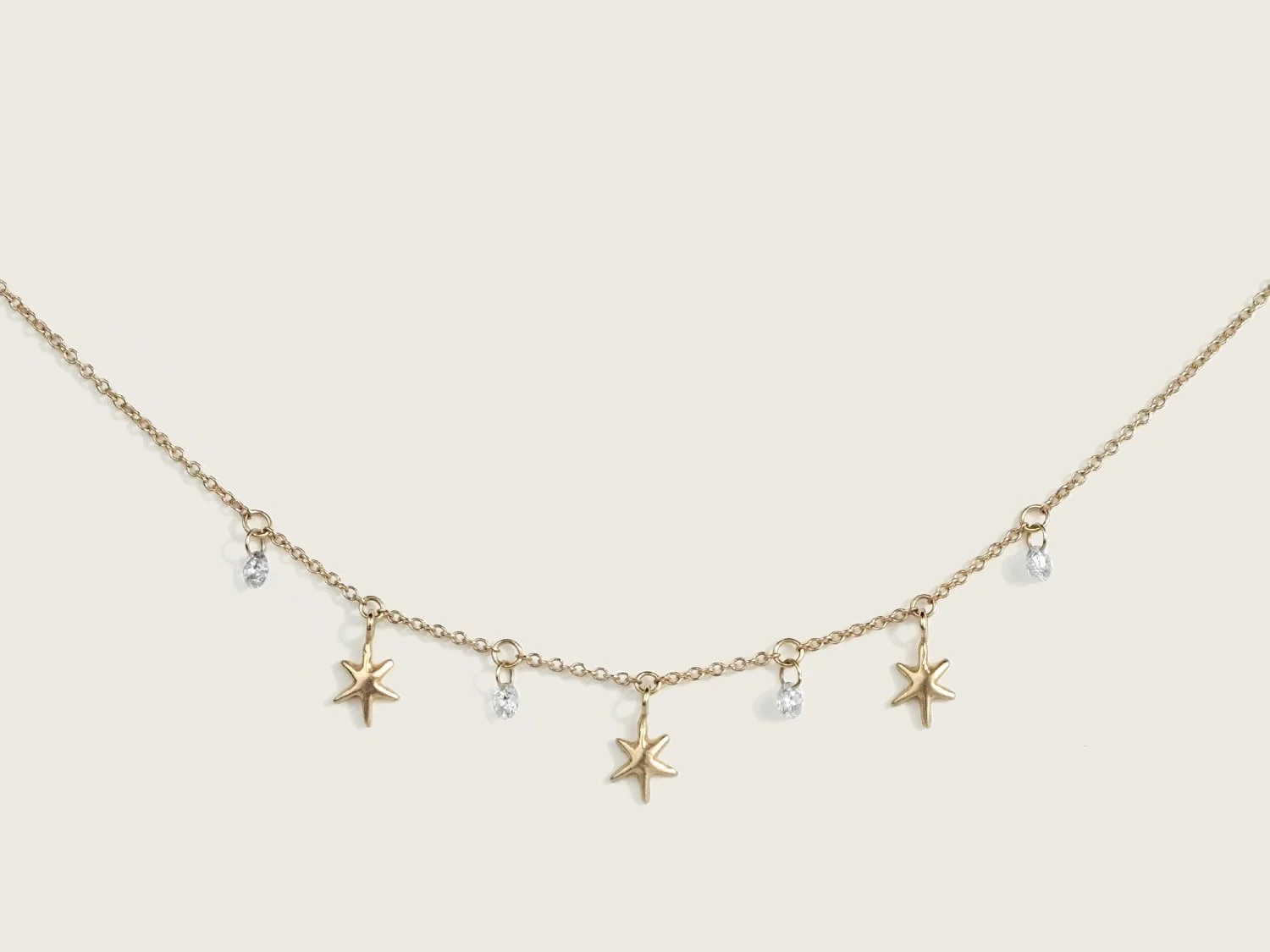 Gold necklace with hanging gold stars and white diamonds