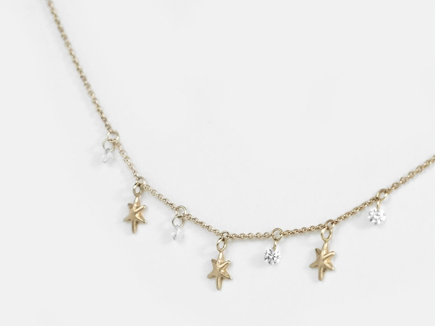 Gold necklace with hanging gold stars and white diamonds