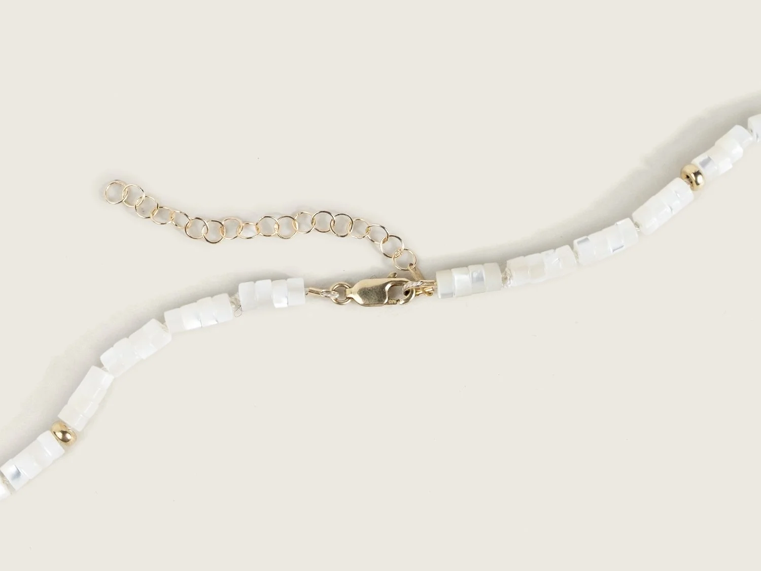 Close up of a lobster-style closure on the back of a mother-of-pearl beaded necklace