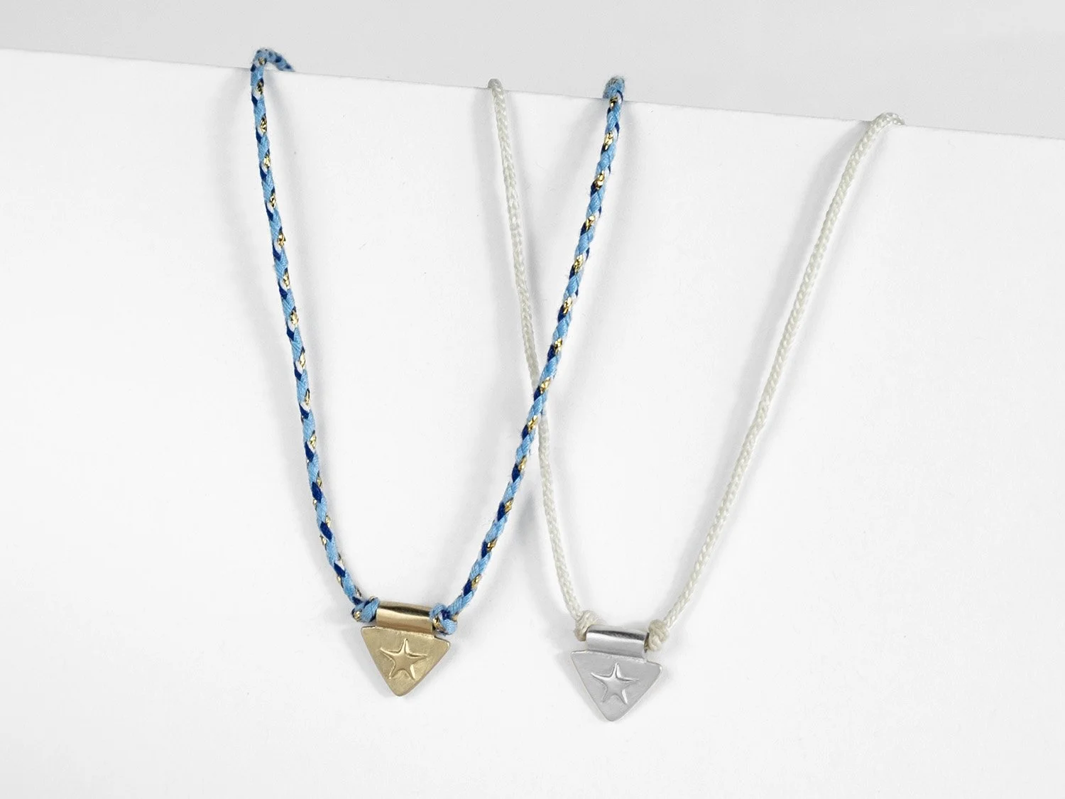 Pair of triangle-shaped silver charms with raised star on braided cords
