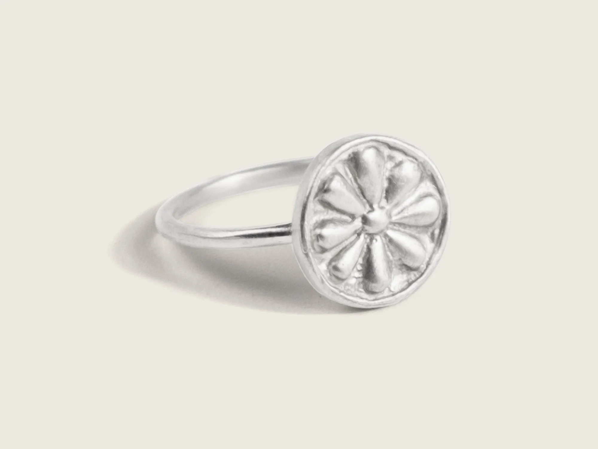 Silver ring with a thin band and an oversized round floral motif on the top