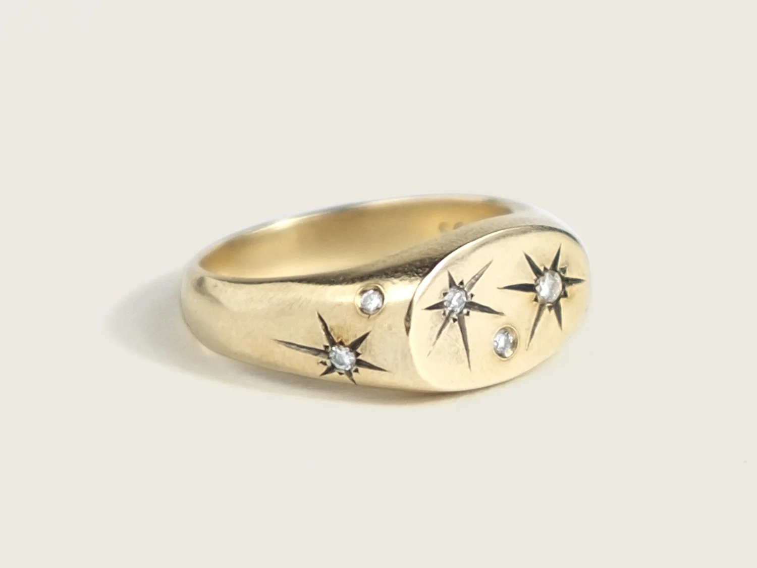 Side view of a wide gold signet ring with star-set diamonds all over the top