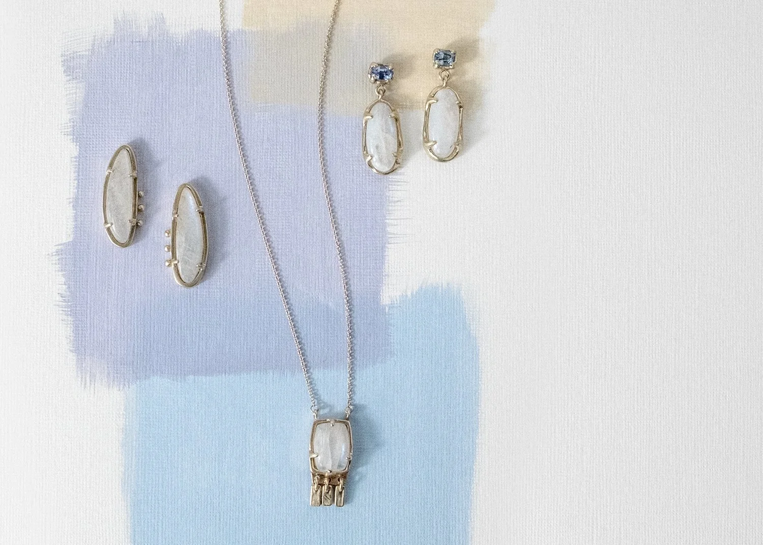Moonstone and gold necklace and earrings on a painted background