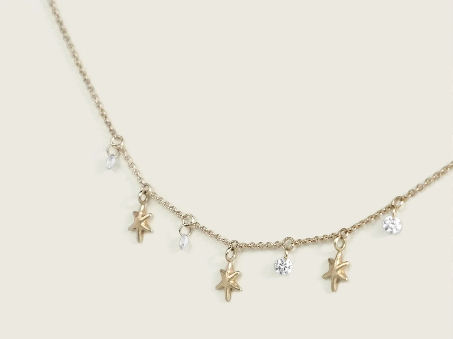 Gold necklace with hanging gold stars and white diamonds