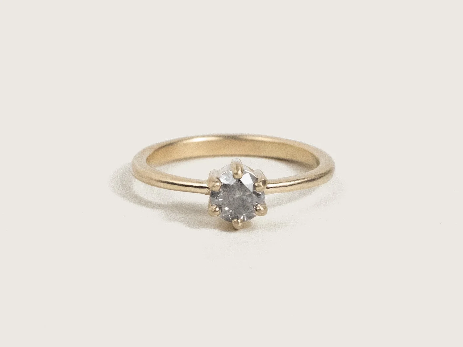 Gold solitaire-style ring with a gray salt & pepper diamond