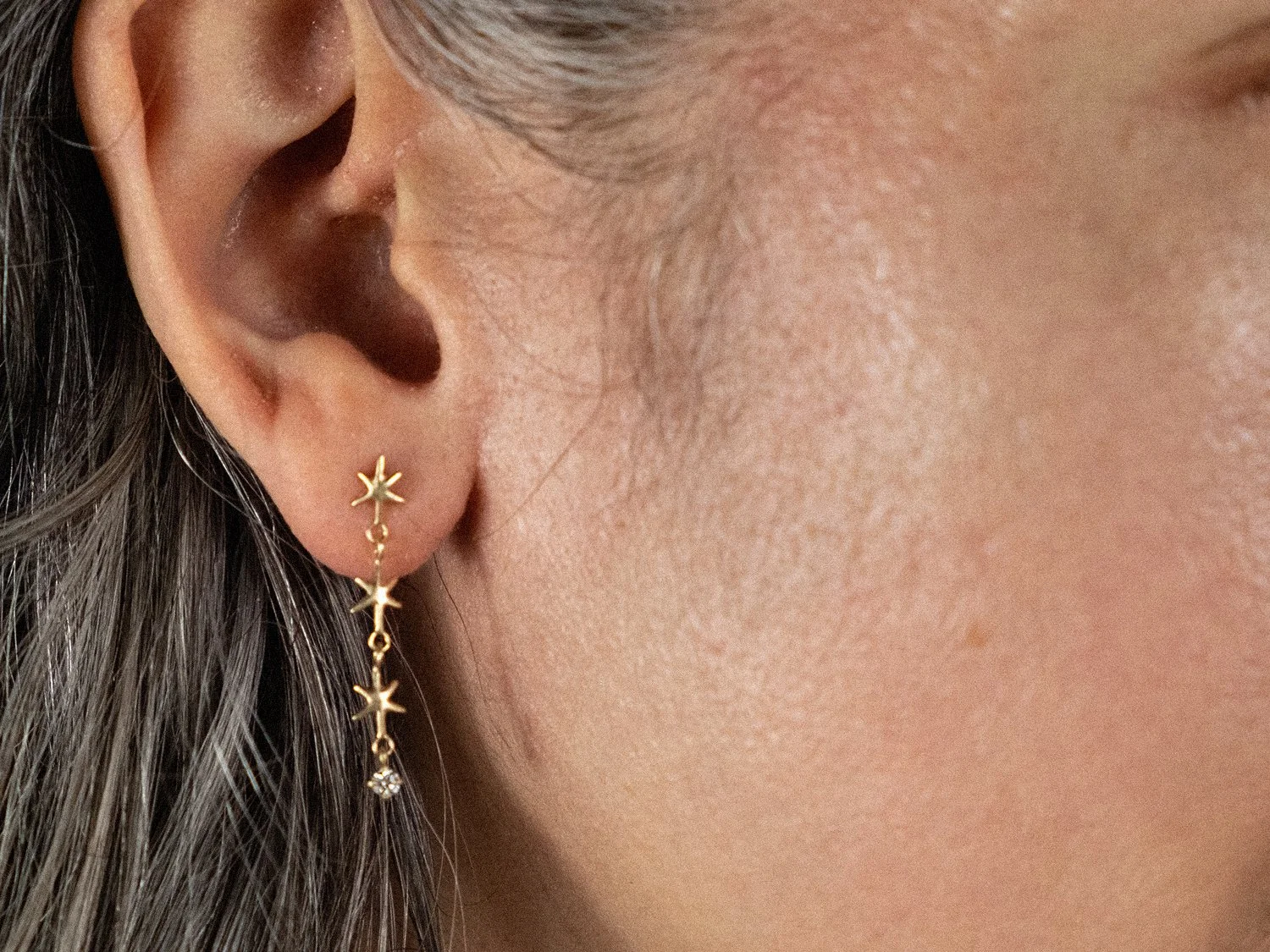 Close up on a model wearing gold star earrings