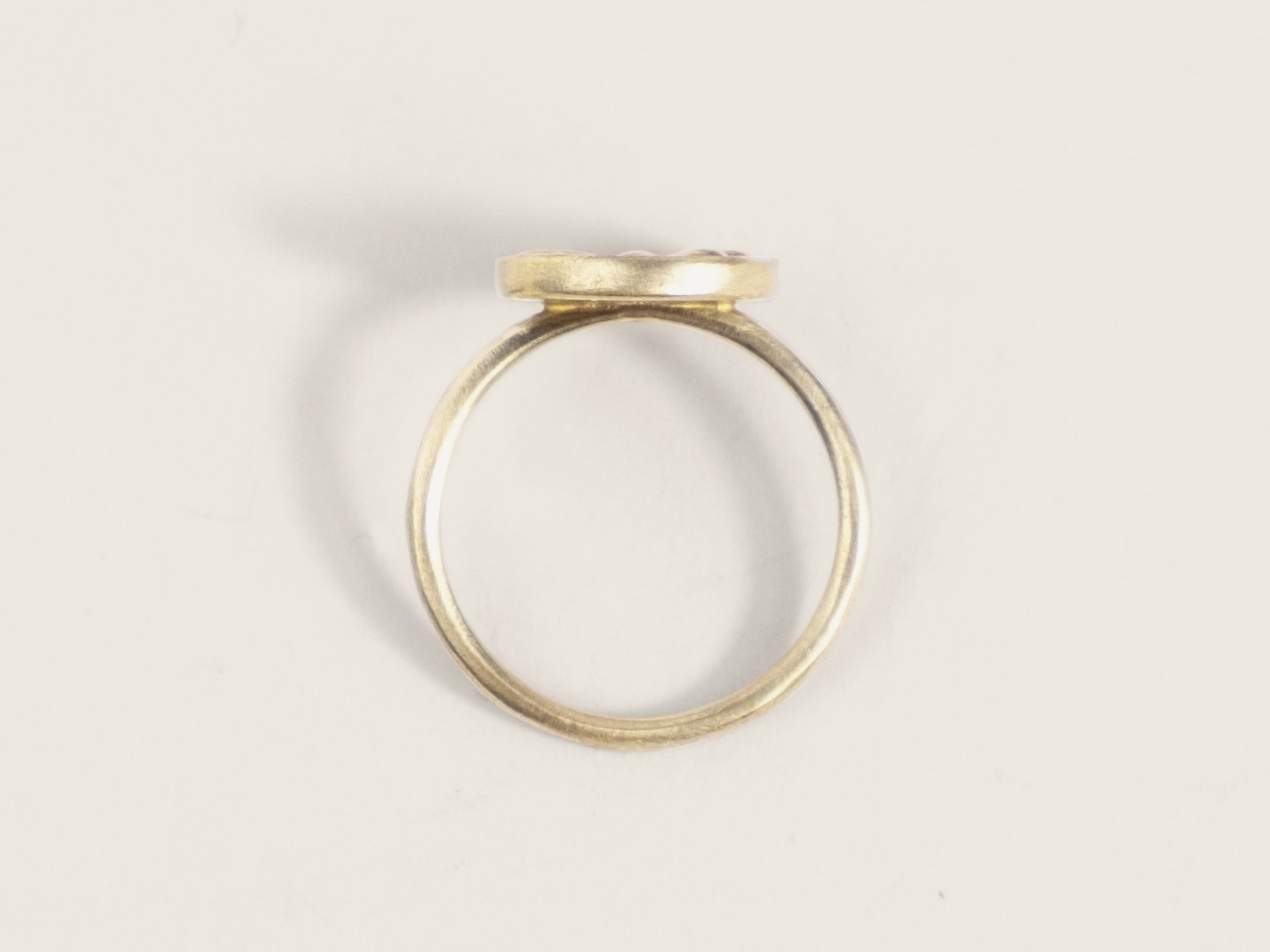 Overhead view of a thin gold ring with an oversized, round floral motif on top (Copy)