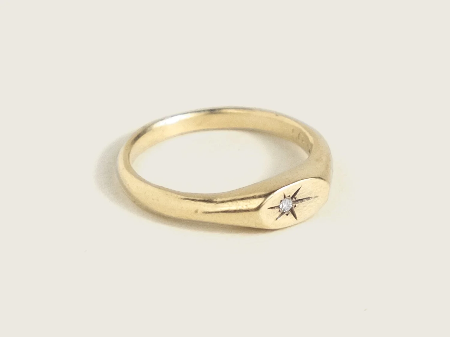 Slim gold signet ring with a star-set diamond on the top face