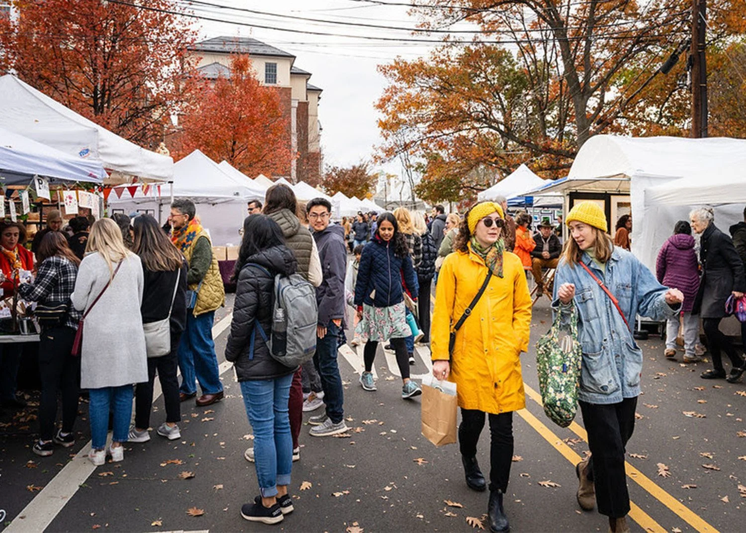 Shoppers walking along a street lined with white tents