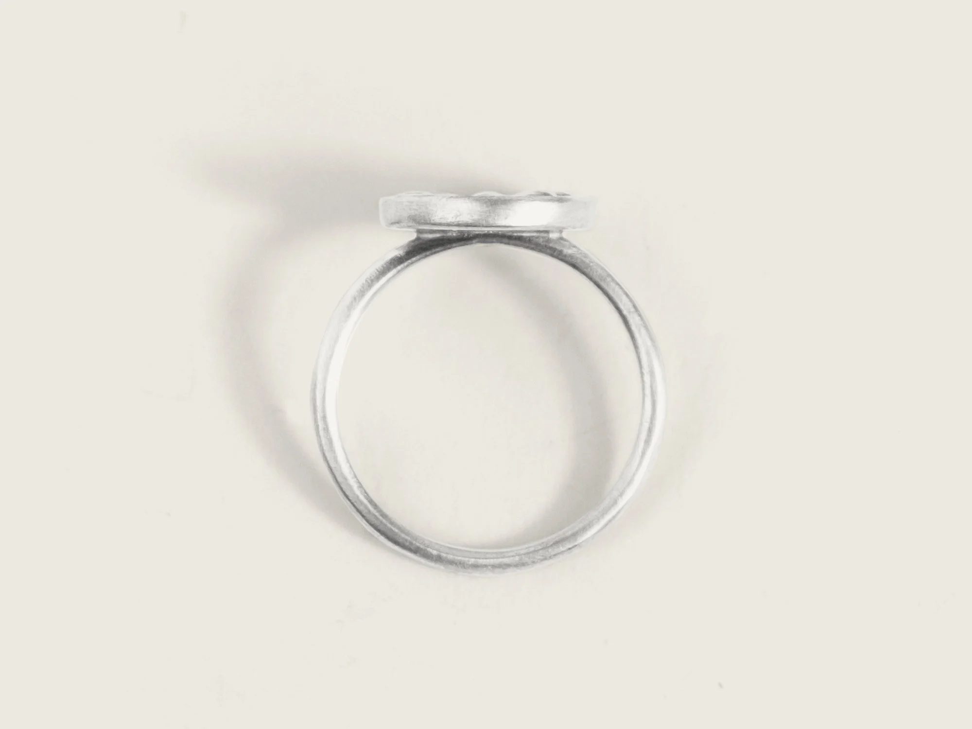 Overhead view of a silver ring with a thin band and an oversized round floral motif on the top