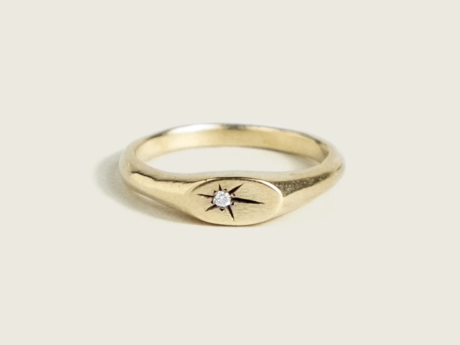 Slim gold signet ring with a star-set diamond on the top face