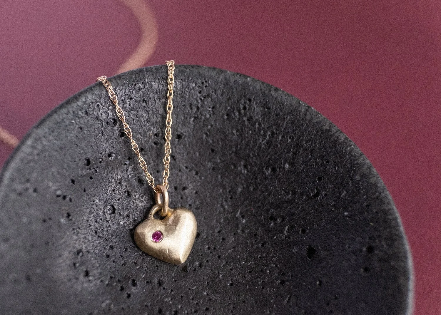 Gold heart-shaped charm in a black ceramic dish