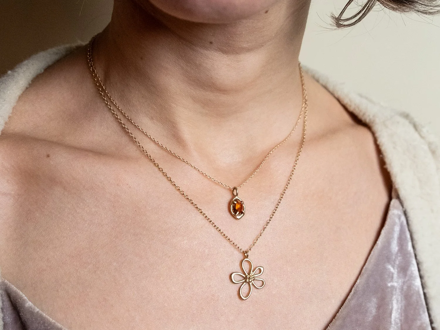 Female model wearing 2 gold charm neckalces in different lengths