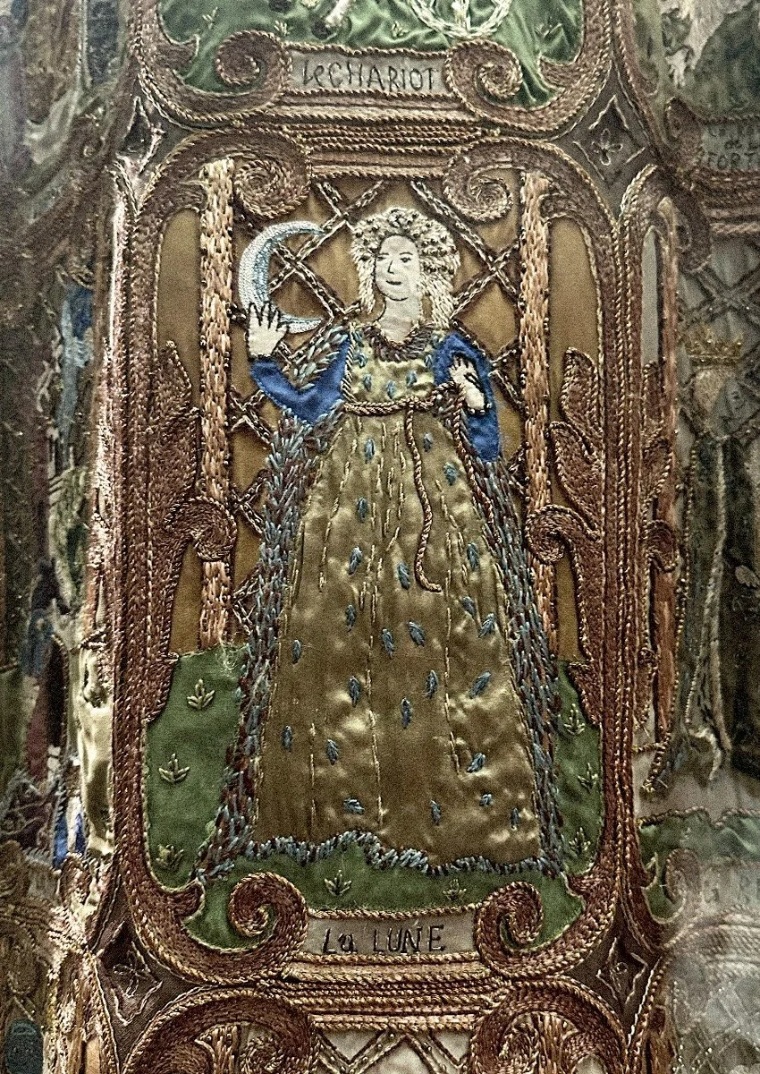 Close up of embroidery depicting a woman holding a crescent moon