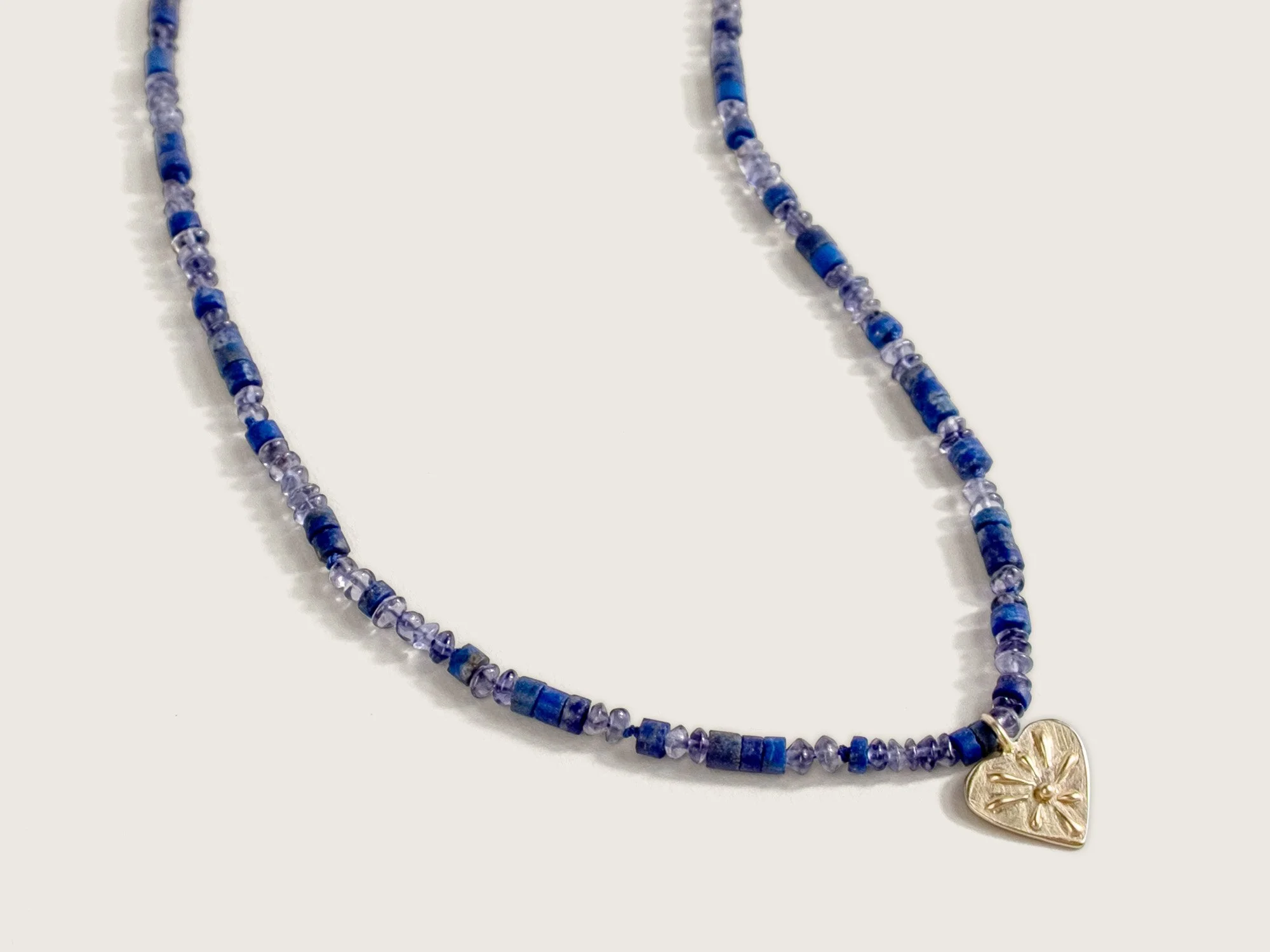 Necklace with beads in dark-blue indigo stones and a center gold heart pendant