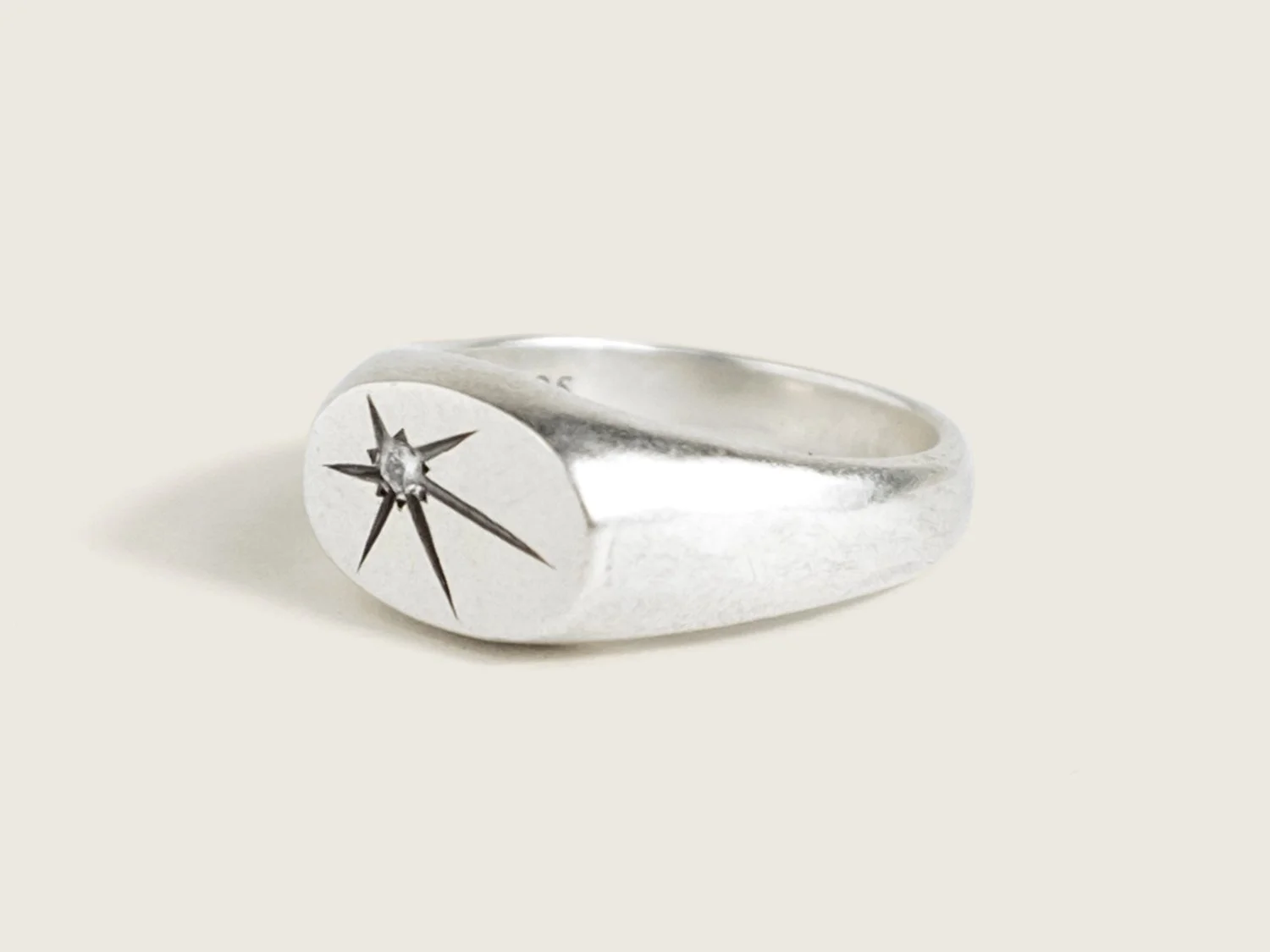 Wide silver signet ring with a single star-set diamond on the flat face