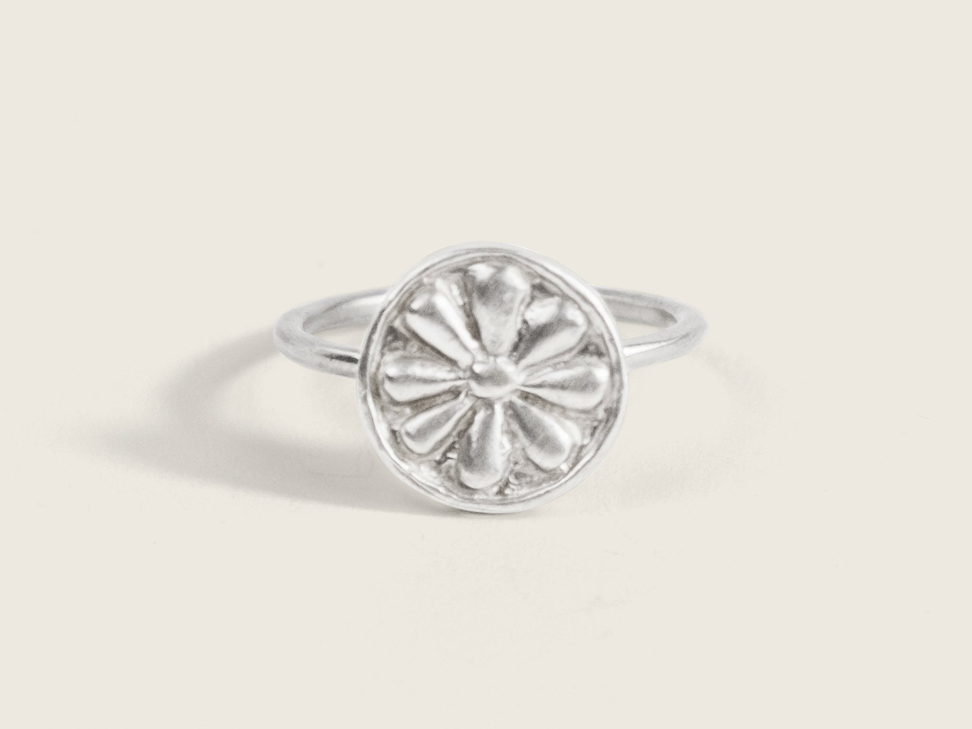 Silver ring with a thin band and an oversized round floral motif on the top