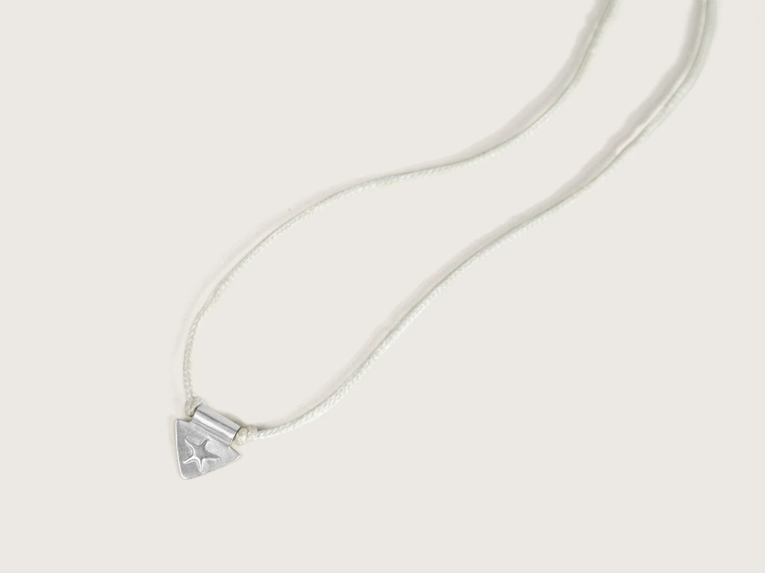 Silver triangle and star charm on an ivory cord