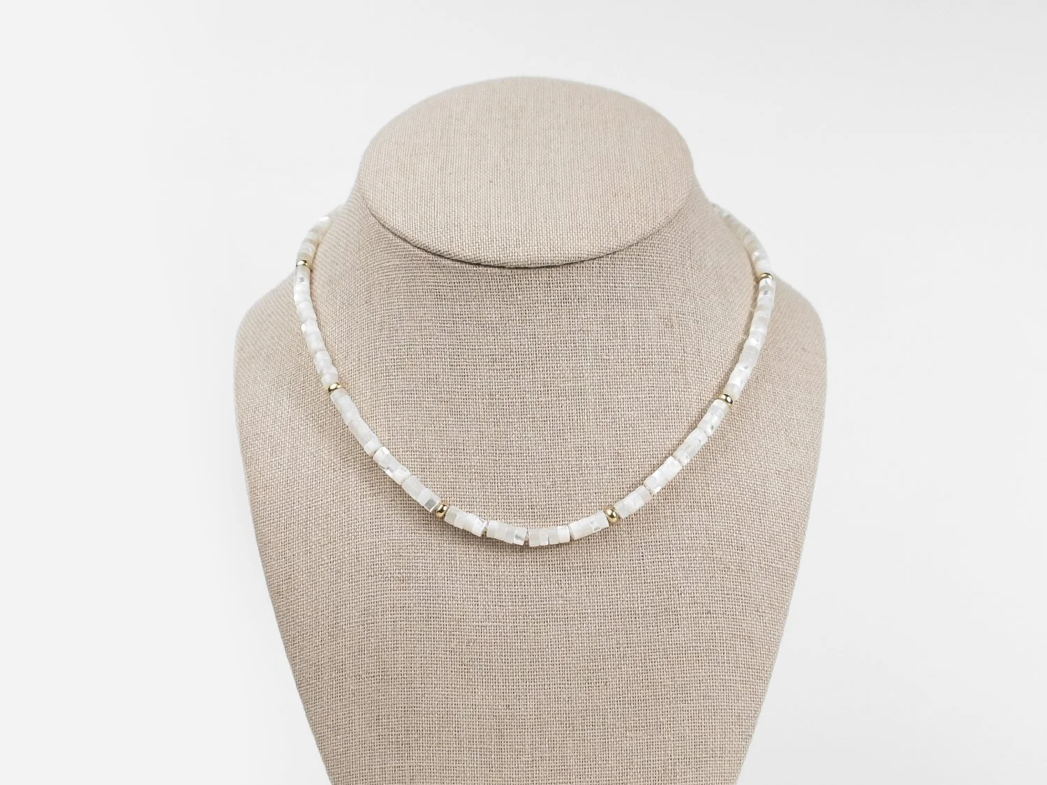 Mother of pearl and gold bead necklace on a linen bust